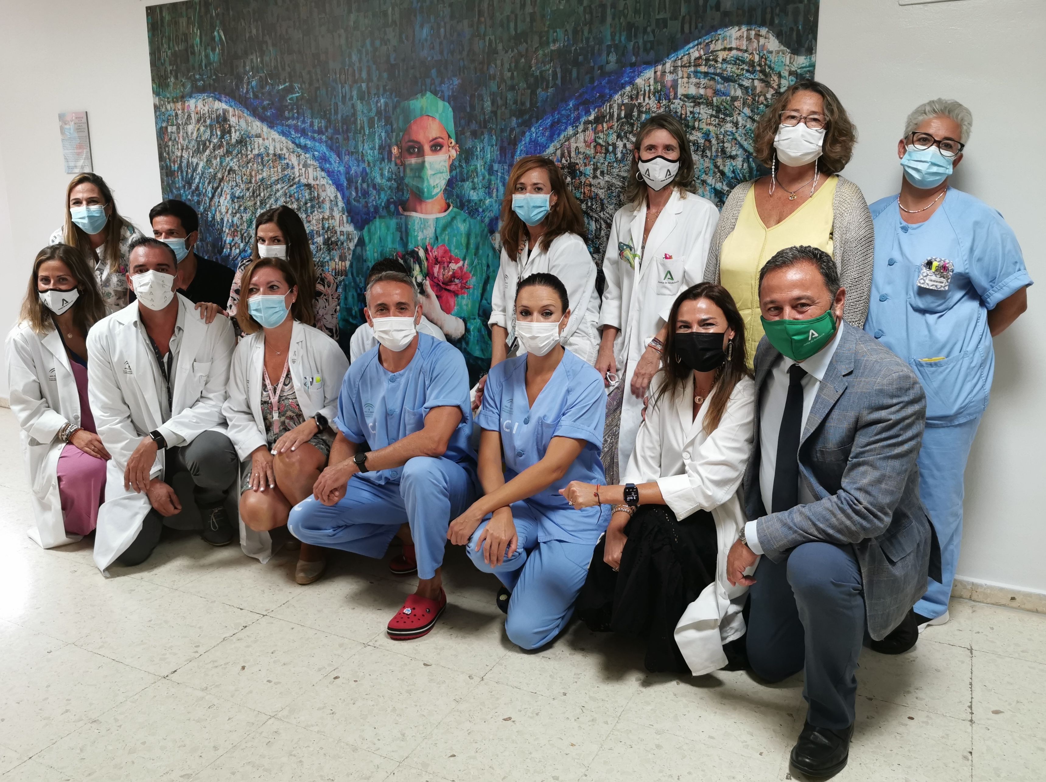 Más de un millar de rostros aunados en una sola foto como homenaje simbólico al compromiso permanente para con el paciente Una foto de fotos simboliza el reconocimiento con el que la dirección del Área de Gestión Sanitaria Sur de Sevilla agradece públicamente a cada uno de sus más de 4.000 profesionales el esfuerzo y dedicación permanentes durante la pandemia. Se trata de un fotomosaico, instalado en el Hospital Universitario de Valme, que se ha construido con la unión de rostros de los profesionales. La iniciativa se ha extrapolado de una original actividad desarrollada al principio de la pandemia en la Unidad de Cuidados Intensivos de este hospital sevillano. Uno de sus enfermeros y también fotógrafo, José Manuel Andrade, comenzó a realizar retratos de sus compañeros de UCI con mensajes motivadores de los mismos. Uno por uno hasta cristalizar en un collage con todo el personal de este servicio clínico. Sin embargo, al año y medio de esta pandemia, y con el compromiso reforzado y permanente para con el paciente, esta área sanitaria ha querido agradecer con un gesto simbólico y lleno de contenido el trabajo diario desarrollado no sólo por sanitarios, sino por la globalidad de profesionales en sus distintos ámbitos de conocimiento y en los centros sanitarios del sur de la provincia.  De ahí que este gran mural sea una muestra de agradecimiento a todo el personal sanitario, de servicios, gestión y administración del Área de Gestión Sanitaria Sur de Sevilla. Como subraya la directora gerente de esta área sanitaria, Mª Jesús Pareja, “conforma un homenaje a la solidaridad permanente de este colectivo durante más de un año de pandemia”.  Al acto organizado para la visualización pública e inauguración del mural ha asistido el delegado del Gobierno de la Junta de Andalucía en Sevilla, Ricardo Sánchez, junto a la delegada territorial de Salud y Familias en Sevilla, Regina Serrano. Ambos acompañados por la directora gerente del Área de Gestión Sanitaria Sur de Sevilla y su equipo directivo, con la asistencia de los profesionales de la Unidad de Cuidados Intensivos impulsores de esta original iniciativa. Enfermera con alas de ángel a modo de simbología protectora El diseño del mosaico está definido por la figura de una enfermera con alas de ángel cargada de simbología. La elección de este perfil profesional responde al rol principal en el cuidado de los pacientes y cercanía con el paciente; máxime cuando la pandemia ha obligado a restringir el acompañamiento por parte de la familia. Precisamente, las alas de ángel aluden al aspecto metafórico que algunas religiones le conceden para proteger, sanar y enseñar. En este caso, brindando la mayor calidad asistencial en el proceso de salud y hasta el acompañamiento en los últimos momentos de vida marcado por las restricciones de seguridad Covid. Destacar que la modelo que ha prestado su imagen para la foto principal es una enfermera de la UCI del Hospital Universitario de Valme: Mª de los Ángeles Risco. Junto a ella ha colaborado en el área artística también otra enfermera de Intensivos del hospital sevillano: Amparo Castillo. El mural, cuyas medidas corresponden a 3 metros de ancho por 2 de alto, luce en un lugar accesible y de paso tanto de profesionales, pacientes y familiares en la planta baja de este centro hospitalario tras cruzar el hall principal. Ubicación relevante para dos rostros especiales En total son 1.200 retratos de profesionales los que unidos uno a uno componen la silueta y el contenido de la foto principal del mosaico. Una enfermera creada con fotos de médicos, enfermeros, auxiliares de enfermería, técnicos, celadores, informáticos, limpiadoras, administrativos, personal de gestión, mantenimiento y equipo directivo. Sin embargo, hay dos rostros a los cuales este reconocimiento les dedica un cariño eterno. Se trata de las dos pérdidas producidas entre las filas del Área de Gestión Sanitaria Sur de Sevilla en lo que va de pandemia. En diciembre de 2020 nos abandonó María del Carmen Carrasco Mialdea, matrona de atención primaria en el centro de salud `Nuestra Señora del Castillo´ en Lebrija, de 62 años de edad. En enero de 2021 falleció Fernando Caba Barrientos, de 66 años de edad, jefe de sección del servicio de Anestesiología de este servicio clínico. Ambos hicieron frente a una larga lucha por superar las complicaciones derivadas del virus. Este recuerdo especial a los dos profesionales que ya nos dejaron tiene como correlato su ubicación relevante en la disposición del mosaico. El homenaje a los compañeros fallecidos incluye su foto en la rosa que sostiene la modelo al lado del corazón. Además, al objeto de otorgarles más visibilidad, se ha disminuido la opacidad en ambos retratos.